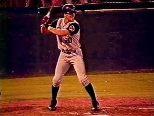 A Tyler Roughnecks batter in a gray road uniform and black helmet waiting for a pitch, 2001